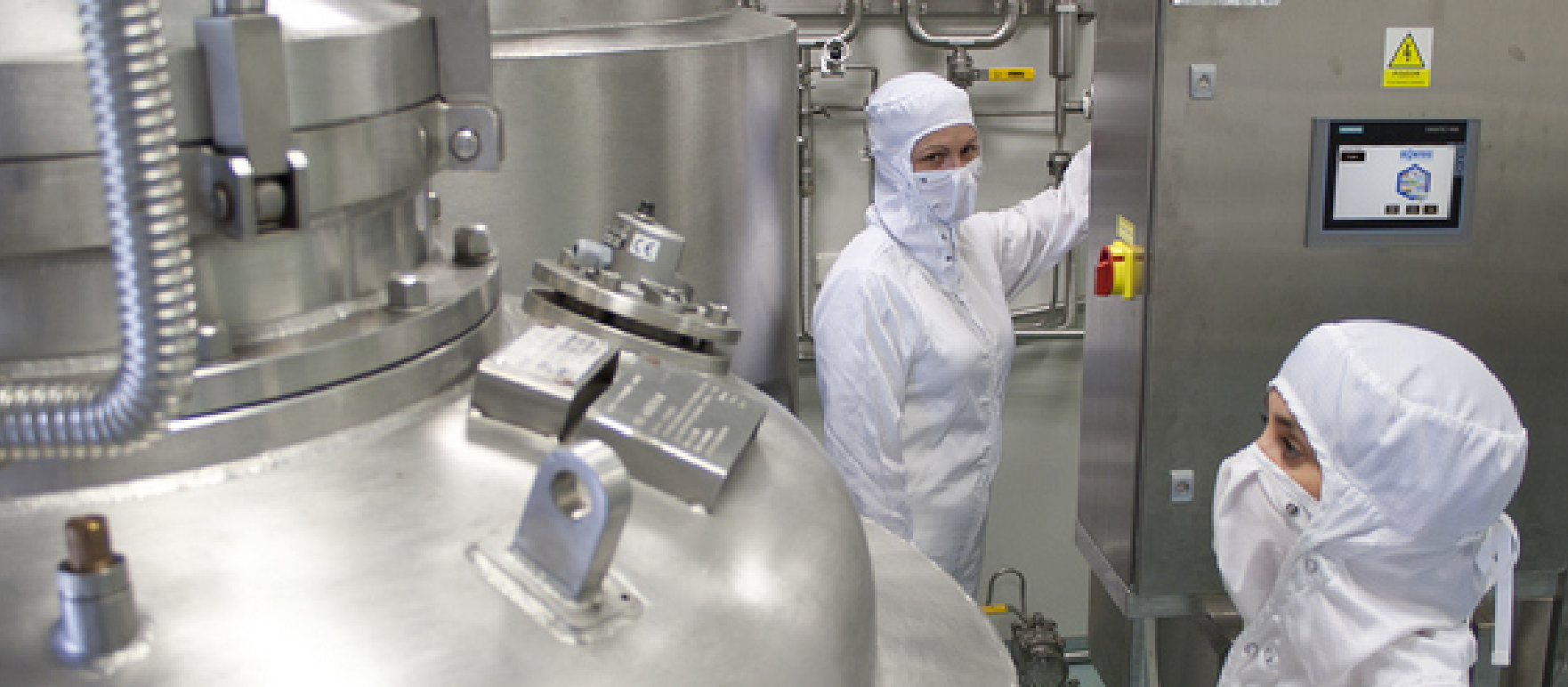 about-us-chemvets Two people in protective suits stand by steel tanks